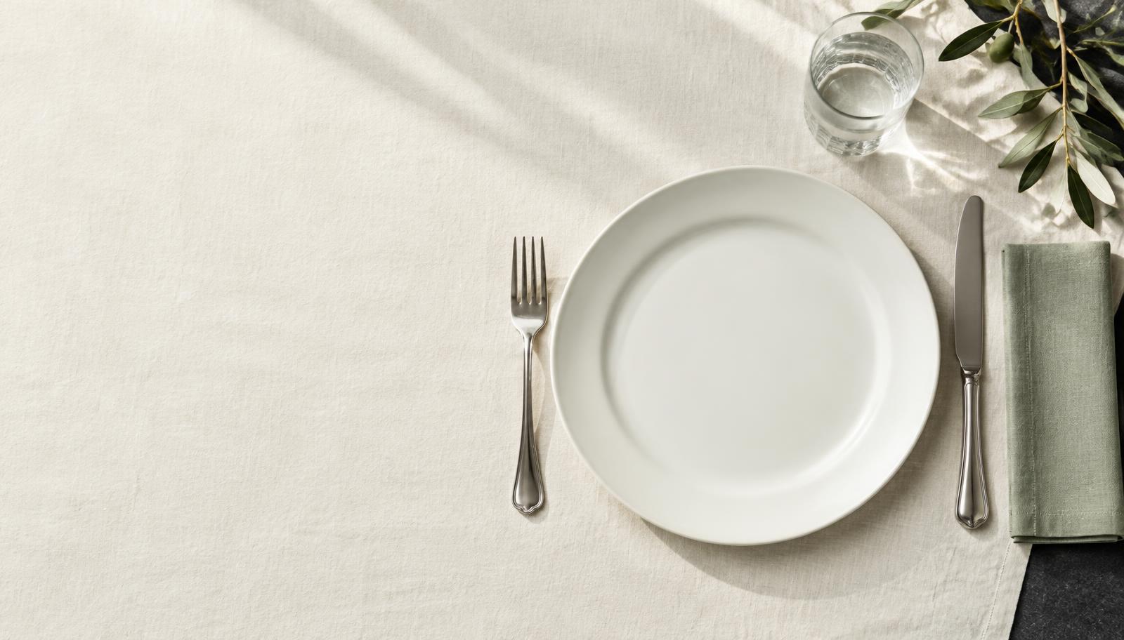 An empty plate, silverware and linen set for a meal; conceptual editorial still life